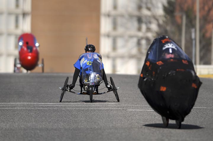 Cara Duberstein, a senior in mechanical engineering at Montana State University, center, peddles through campus Sunday morning during the ASME Human Powered Vehicle Challenge speed endurance event.